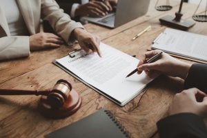 Geschäftsleute verhandeln über einen Vertrag und besprechen die Vereinbarung, während sie gemeinsam in einem sonnigen, modernen Büro arbeiten. Ein unbekannter Geschäftsmann und eine Geschäftsfrau sitzen mit Kollegen oder Anwälten in einer Besprechung.