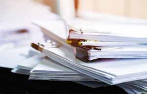 apel von Papierdokumenten in Aktenordnern mit Büroklammern auf einem Tisch im Büro.